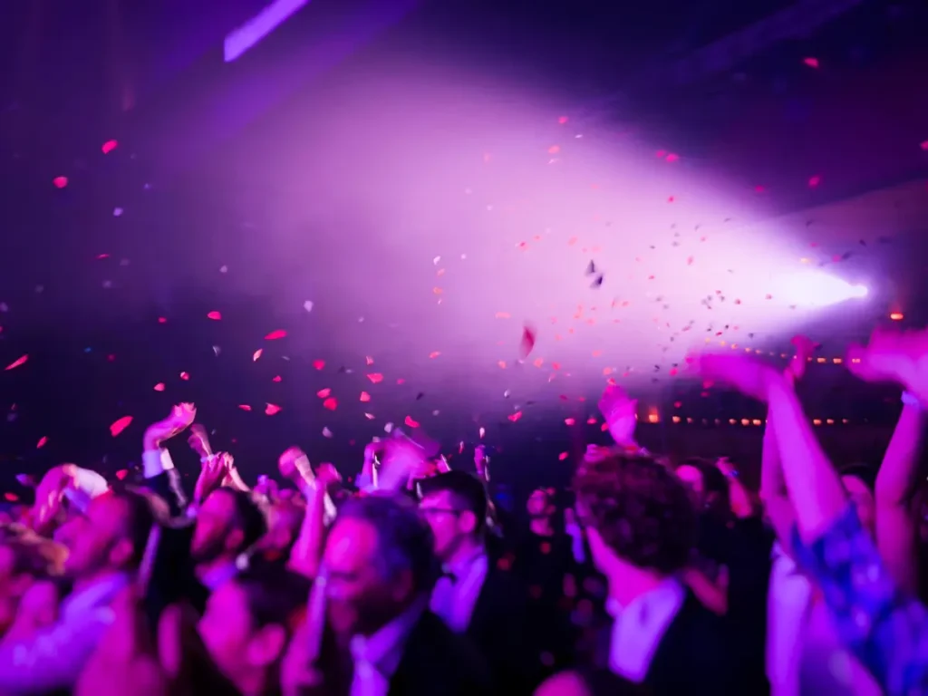 Multitud celebrando y bailando con confeti en una fiesta nocturna